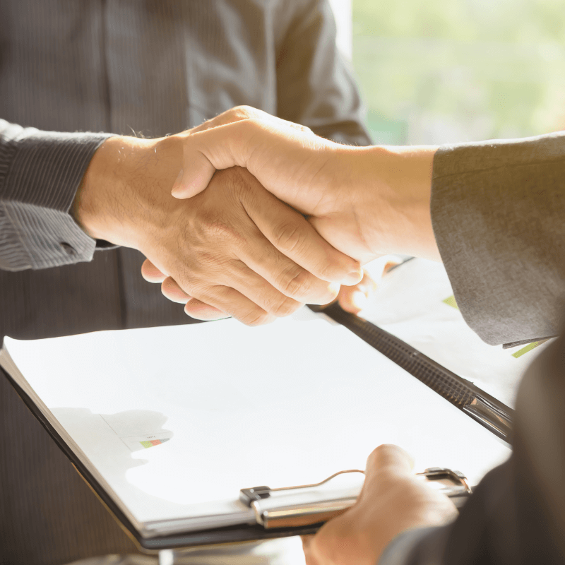 A close-up of a handshake over a contract, symbolizing trust and partnership. Shareholding Agreement services by Prima Consulting ensure business security and family harmony across generations.